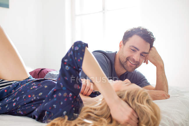Пара лежащих на кровати лицом к лицу улыбающихся — стоковое фото