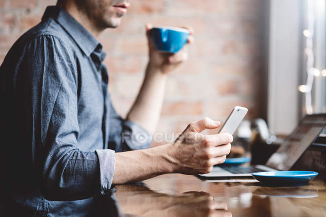 Чоловік використовує мобільний телефон у кафе — стокове фото
