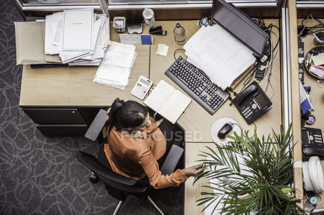 Overhead view of businesswoman busy at office desk — Stock Photo