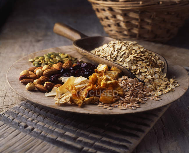 Dried fruit, nuts and oats on wooden plate — Stock Photo