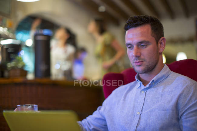 Uomo che utilizza il computer portatile in ristorante moderno — Foto stock