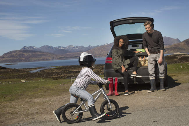 Parents watching son ride bike, Loch Eishort, Isle of Skye, Hebrides, Scotland — Stock Photo
