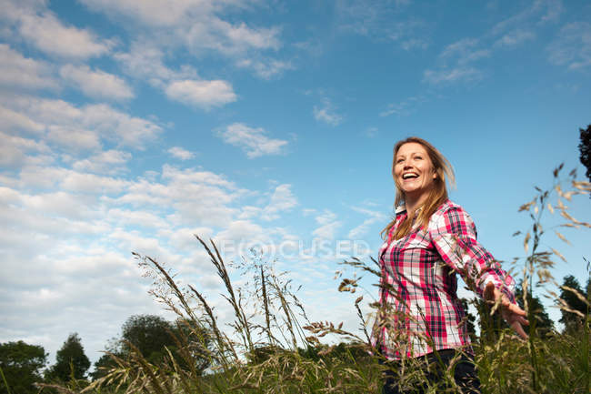 Улыбающаяся женщина ходит в высокой траве — стоковое фото