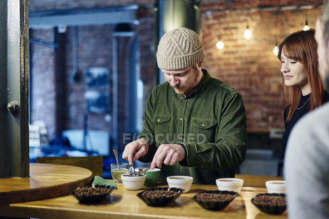 Coffee shop team tasting bowls of coffee and coffee beans — Stock Photo