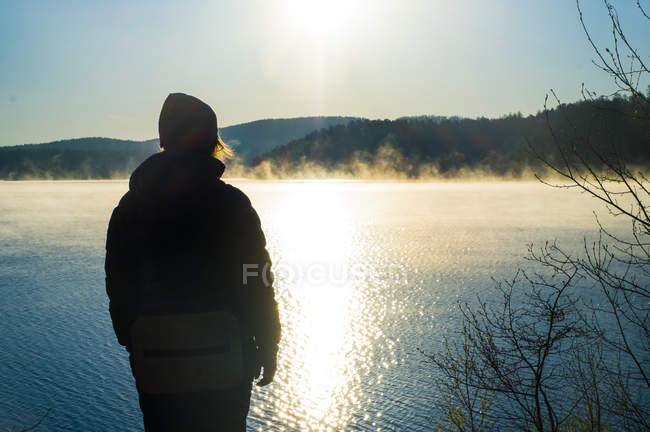 Turista desfrutando de vista por lago ao pôr do sol — Fotografia de Stock