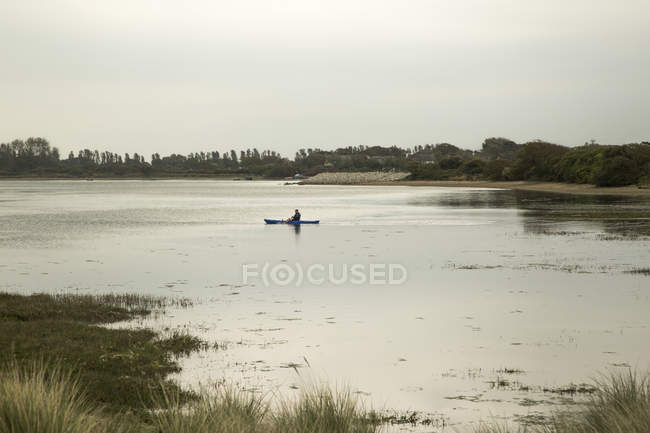 Canoista maschio sagomato sul lago rurale — Foto stock