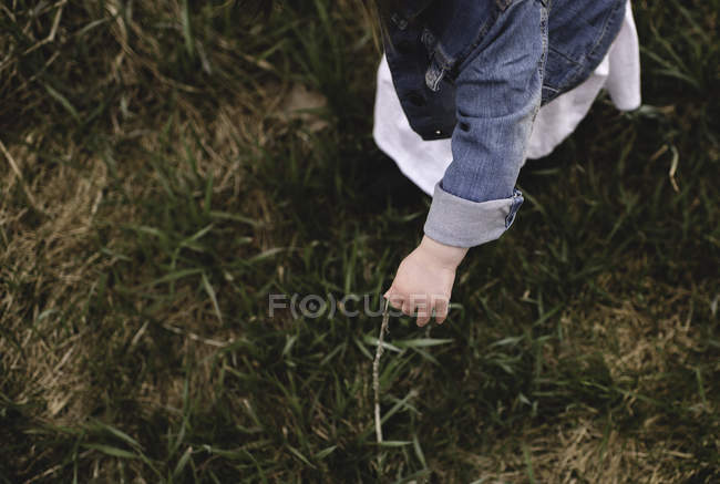 Vue élevée de la jeune fille ramassant de l'herbe dans le champ — Photo de stock