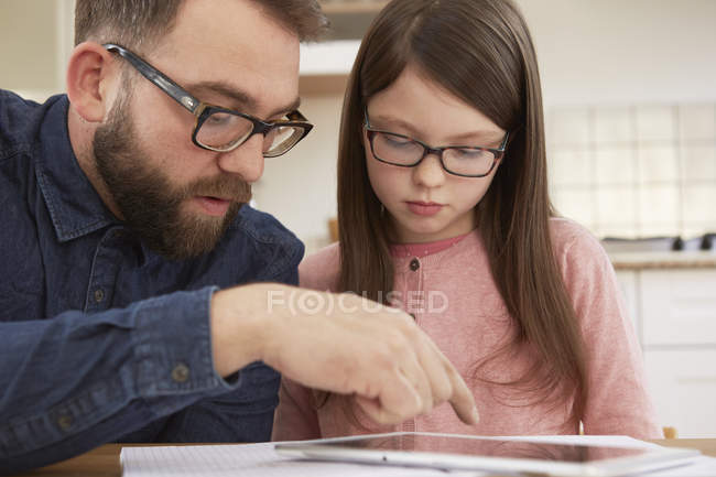 Metà uomo adulto spiegando compiti a casa a figlia a tavola — Foto stock