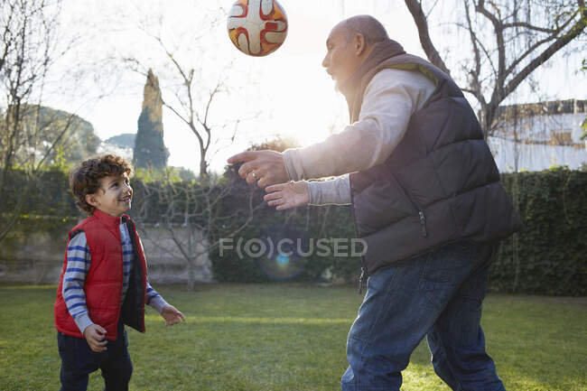 Дідусь і онук грають з футболом посміхаючись — стокове фото