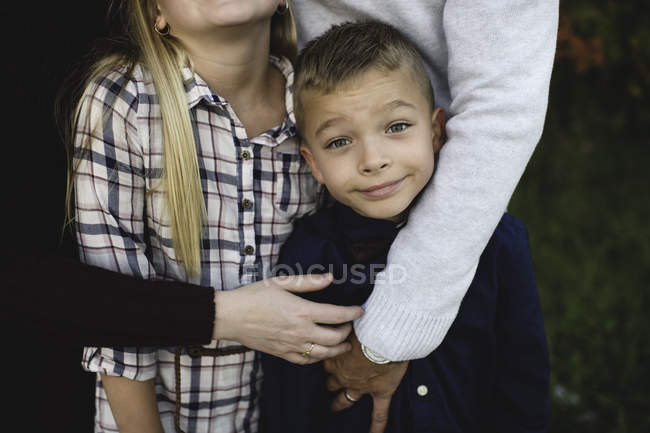Vista recortada de los padres abrazando a hermano y hermana - foto de stock