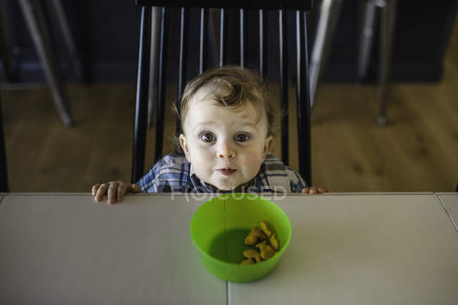 Porträt eines blauäugigen männlichen Kleinkindes, das vom Tisch aufblickt — Stockfoto