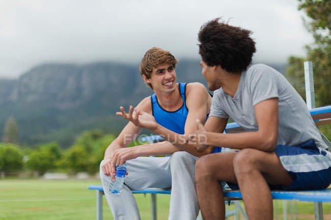 Men talking on bleachers in park — Stock Photo