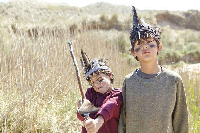 Двоє молодих хлопчиків у вишуканій сукні, тримаючи домашній лук і стрілу — стокове фото