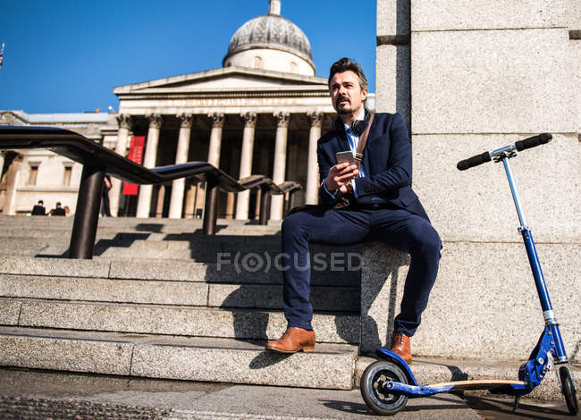 Businessman beside scooter, Trafalgar Square, London, UK — Stock Photo