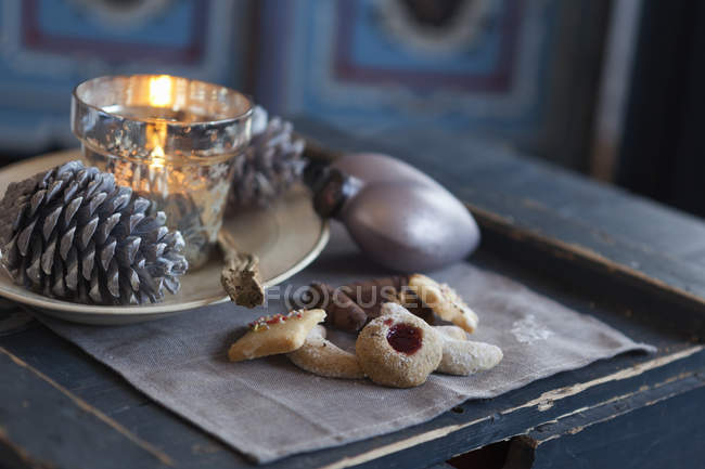Vista de cerca de las galletas, cono de pino y candelabro en la mesa de madera rústica - foto de stock