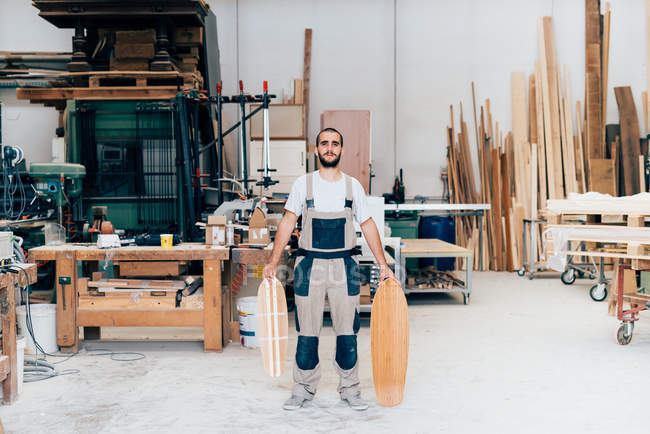 Человек в мастерской со скейтбордами — стоковое фото