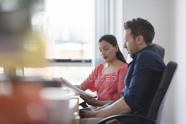Office workers talking while working in office at desk with documents — Stock Photo