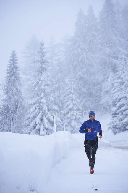 Male runner running in falling snow, Gstaad, Switzerland — Stock Photo