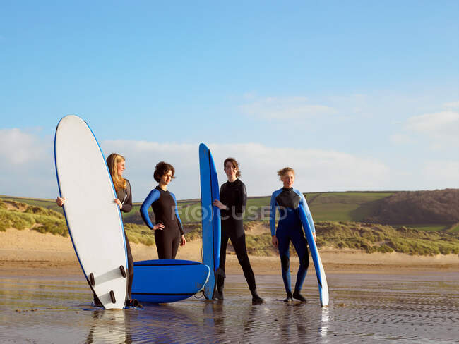 Четыре серфингистки стоят на пляже — стоковое фото