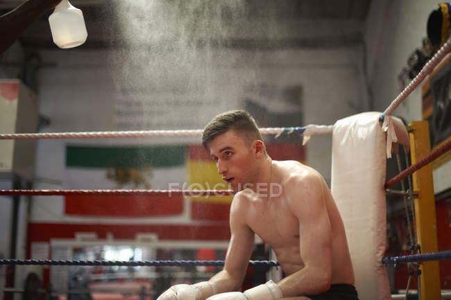 Boxer sitting in corner of boxing ring, exhausted — Stock Photo