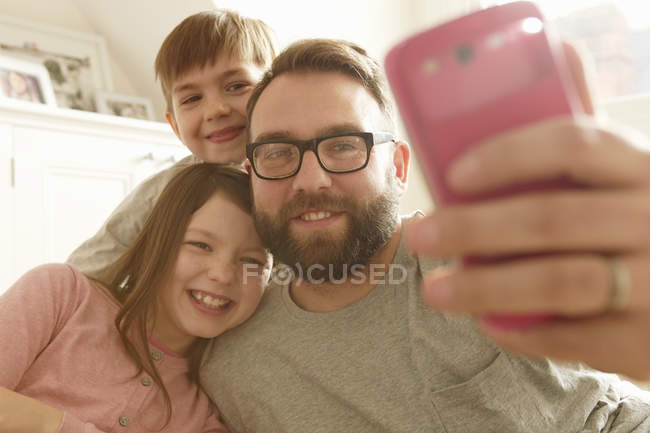 Взрослый мужчина и двое детей делают селфи на смартфоне — стоковое фото
