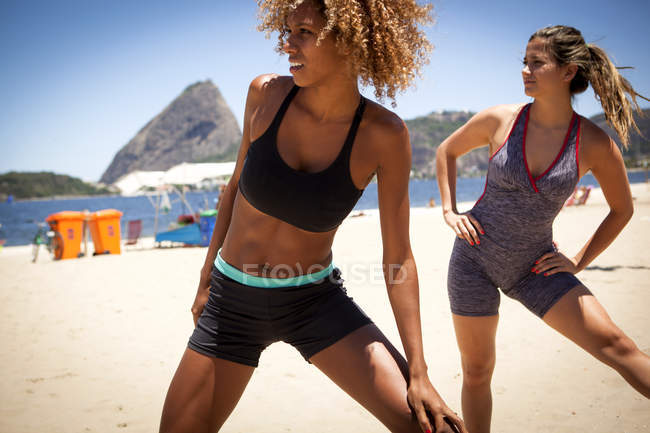 Jovens mulheres se alongando na praia — Fotografia de Stock
