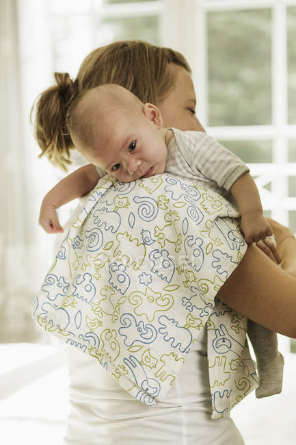 Mãe arrotar bebê filho enquanto carregando-o em seu ombro — Fotografia de Stock