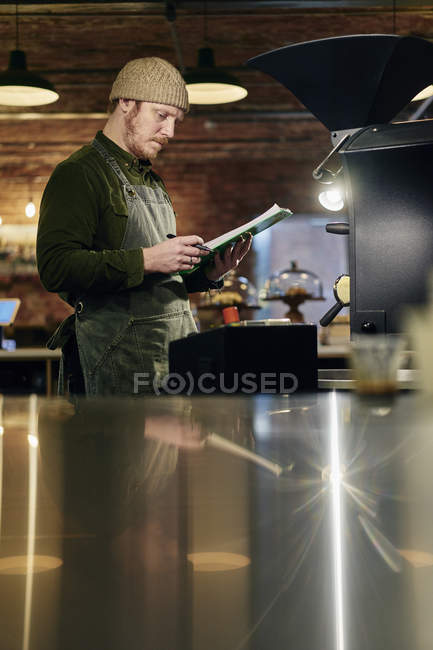 Male coffee shop owner checking coffee roaster — Stock Photo