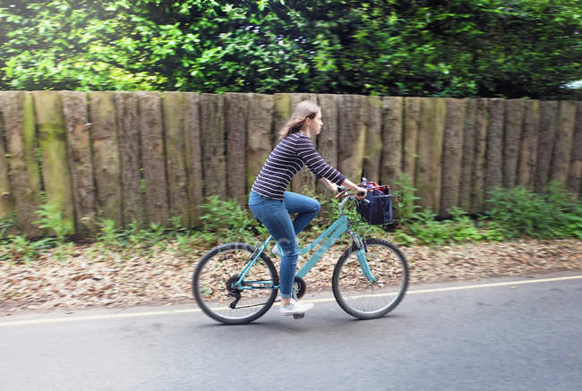 Jovem mulher pedalando na estrada rural — Fotografia de Stock