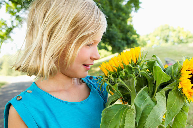 Smiling girl carrying sunflowers — Stock Photo