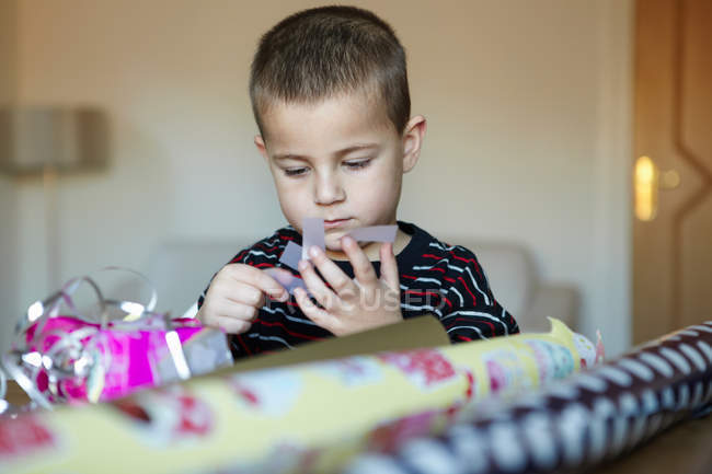 Мальчик упаковывает подарки на стол — стоковое фото