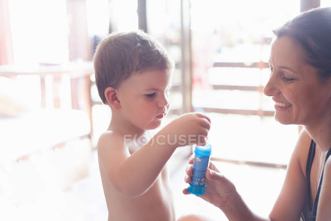 Mère et fils soufflant des bulles à l'intérieur — Photo de stock
