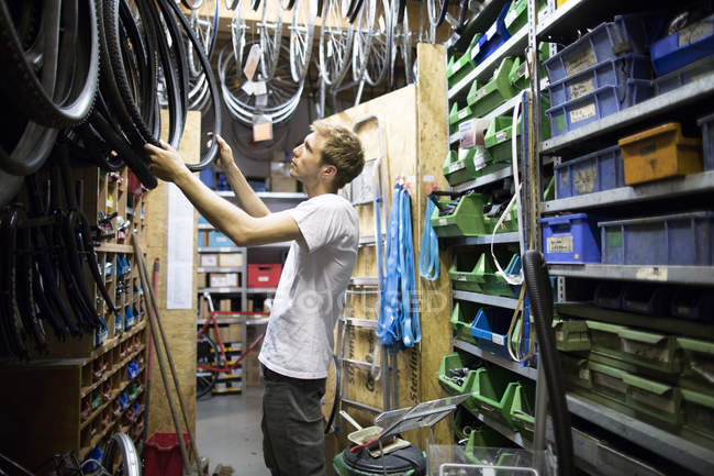 Homem adulto médio na loja de reparação escolhendo pneu de bicicleta — Fotografia de Stock