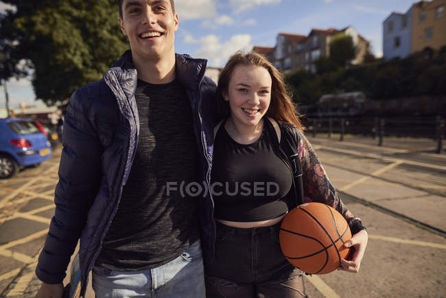Dos amigos caminando al aire libre, mujer joven sosteniendo baloncesto, Bristol, Reino Unido - foto de stock