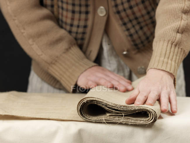Cortado de perto de jovens mulheres designer mãos dobrar tecido de serapilheira — Fotografia de Stock