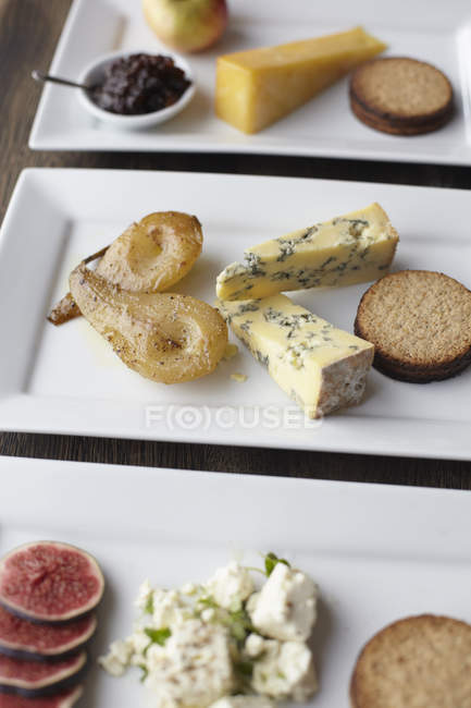 Plates with different cheese and fruits on table — Stock Photo