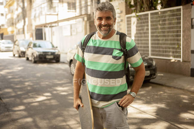 Portrait of mature man carrying skateboard, Rio De Janeiro, Brazil — Stock Photo