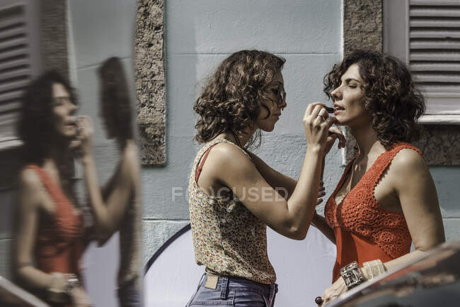 Hinter den Kulissen eines urbanen Mode-Shootings mit Maskenbildnerin, die dem Model Lippenstift aufträgt — Stockfoto