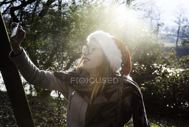 Young woman wearing, outdoors, wearing christmas hat, taking selfie with smartphone — Stock Photo