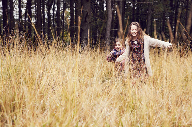 Две молодые девушки бегут по лугу, рука об руку — стоковое фото