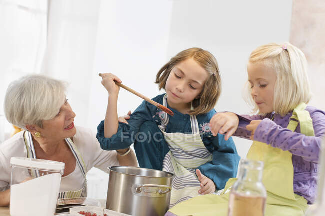 Chicas con la abuela mermelada de cocina - foto de stock