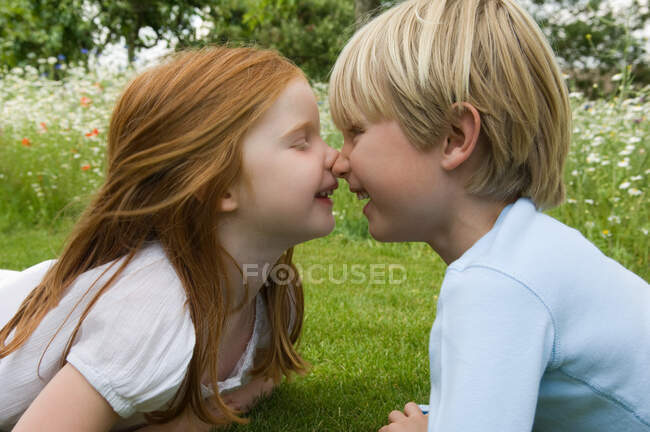 Children touching noses in field — Stock Photo