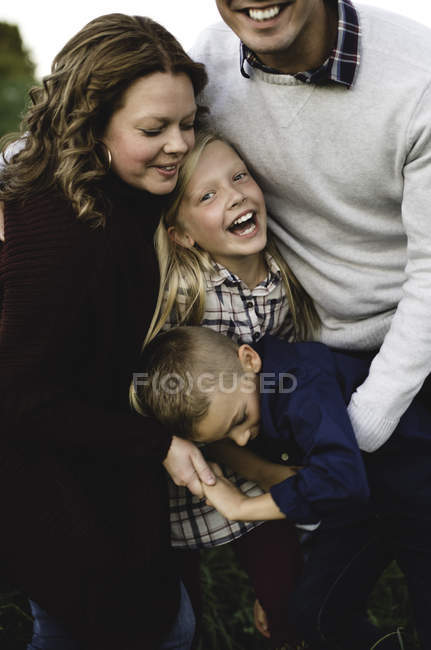 Family hugging and smiling outdoors — Stock Photo