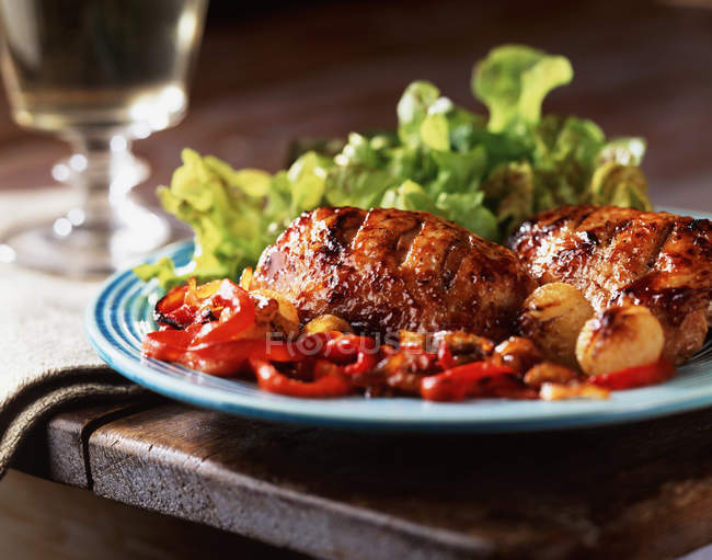 Жареная курица и перец с салатом на тарелке — стоковое фото