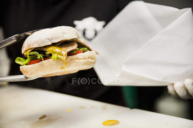 Burger with dripping mustard served from food market stall — Stock Photo