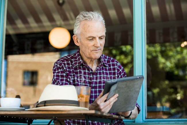 Homme âgé utilisant une tablette numérique au café — Photo de stock