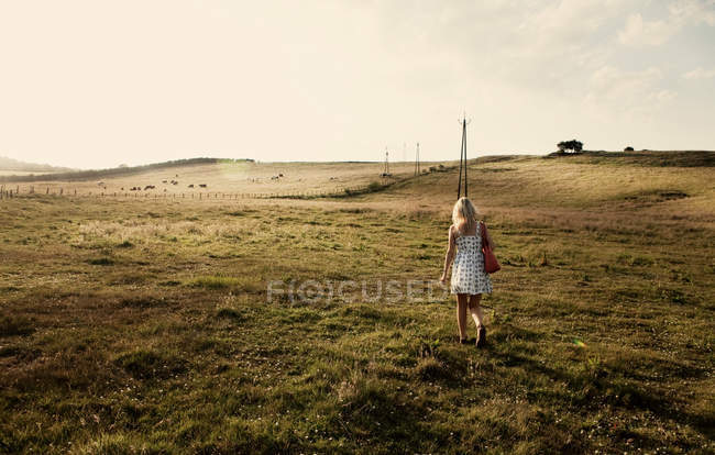 Jeune femme marchant à travers le champ — Photo de stock