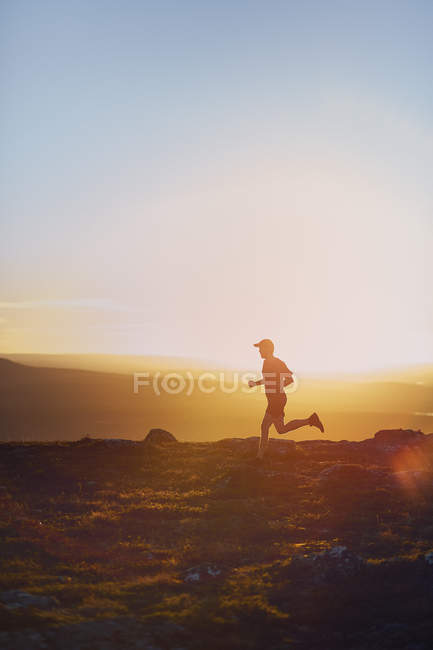 Man trail running on cliff top at sunset, Keimiotunturi, Lapponia, Finlandia — Foto stock