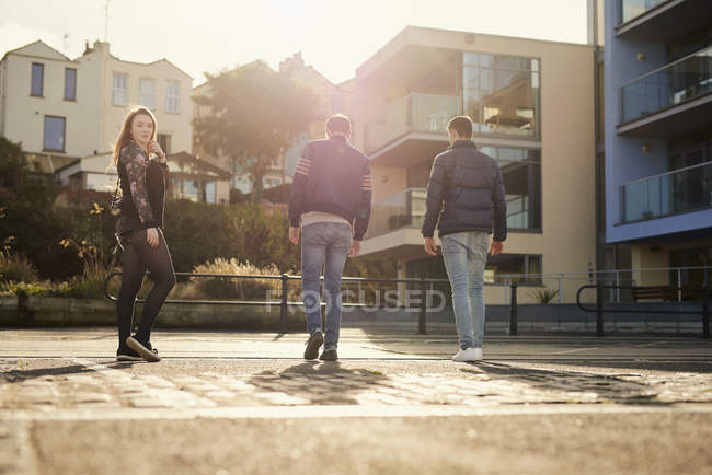 Three friends walking outdoors, young woman looking over shoulder, Bristol, UK — Stock Photo