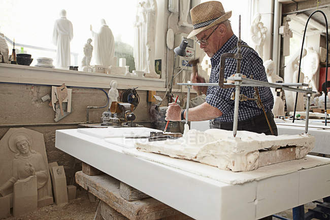Worker chiseling slab of stone — Stock Photo